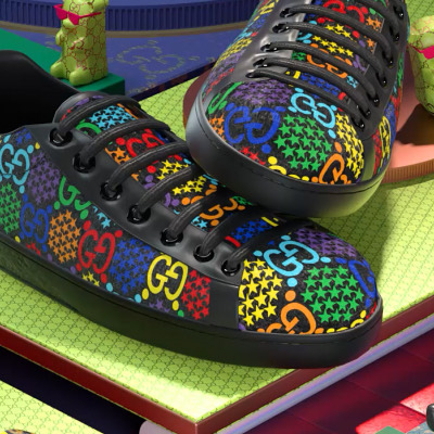 Two black sneakers printed with a multicoloured GG monogram and stars, on green and red blocks.