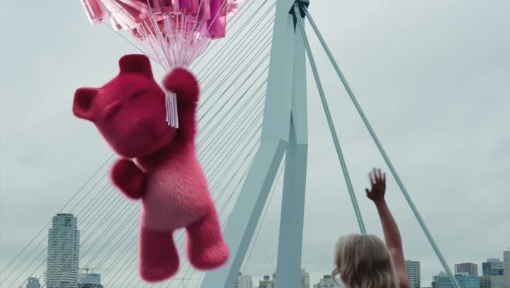 The pink bear climbing a bridge cable above the water.