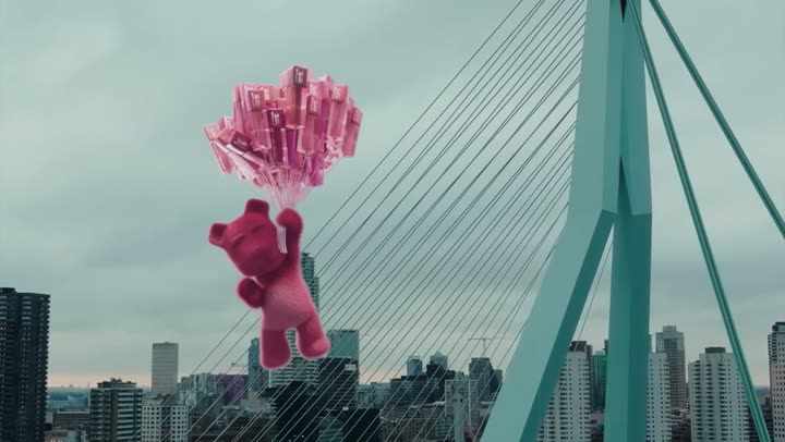 The bear hanging from the bridge with the city skyline behind it.